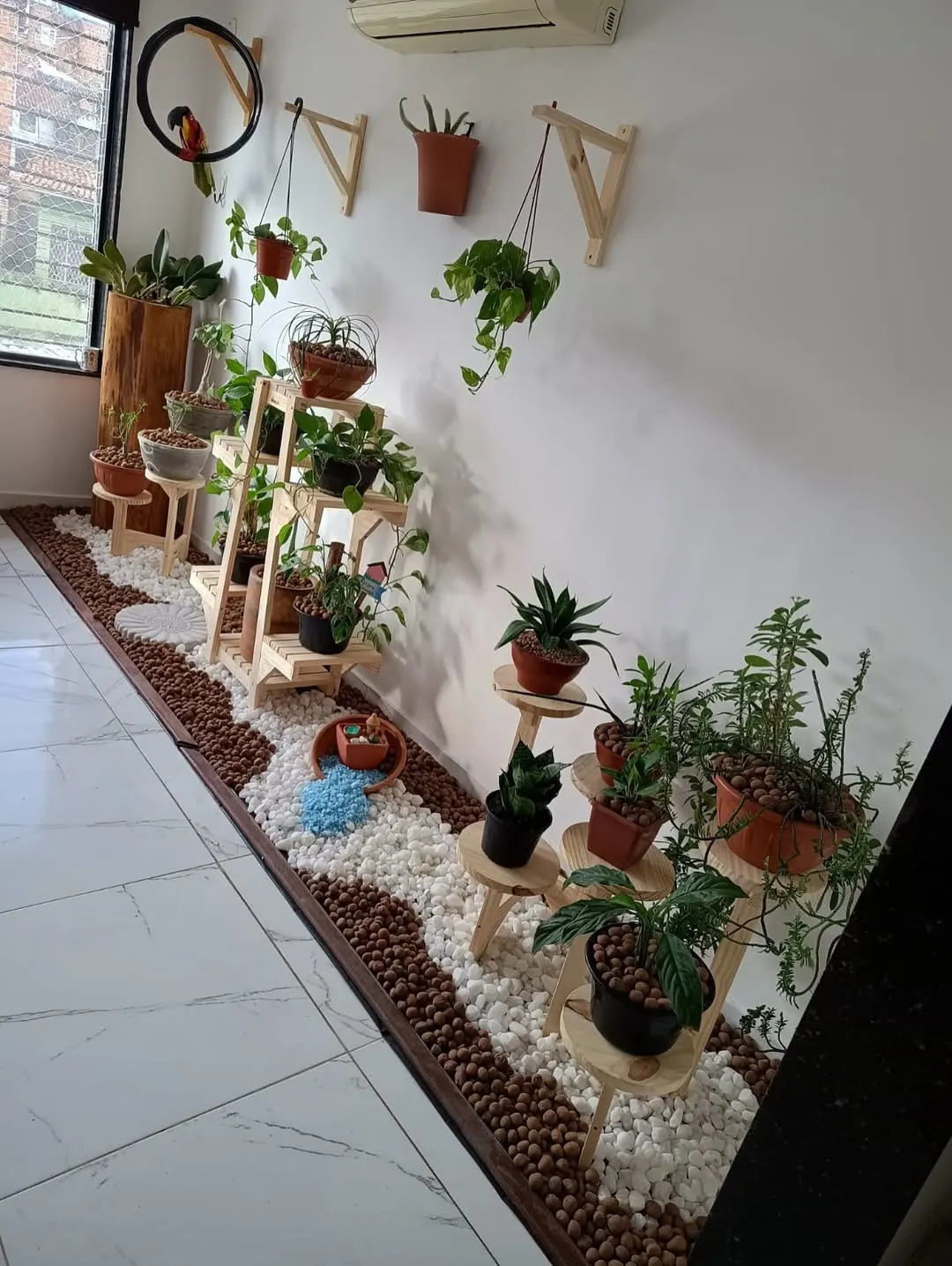 Cantinho de plantas na sala com pallets e pedras.