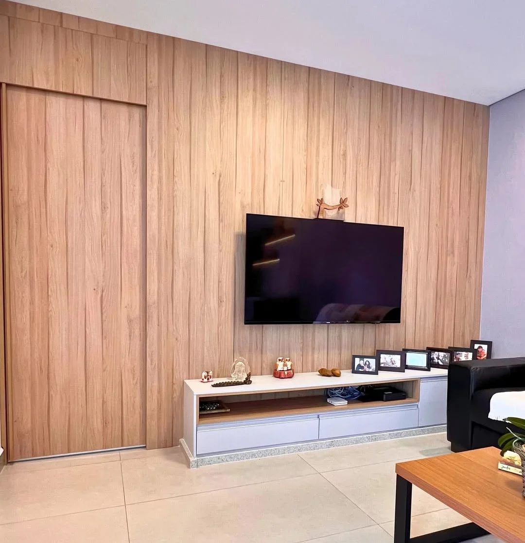 Sala de estar aconchegante com painel ripado e pedaço da porta de madeira também.