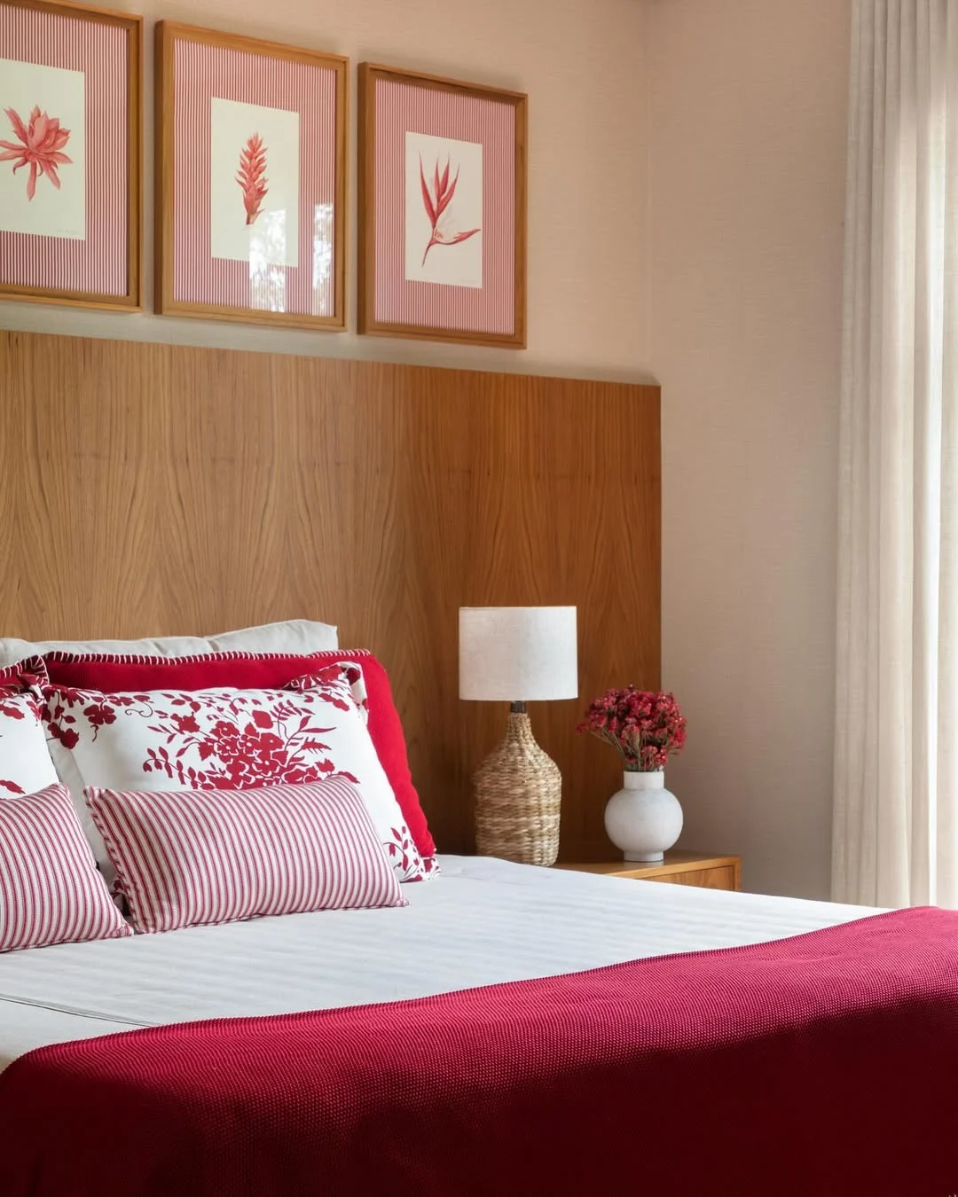 Quarto de adulto com estampas nas almofadas e vermelho como cor predominante.