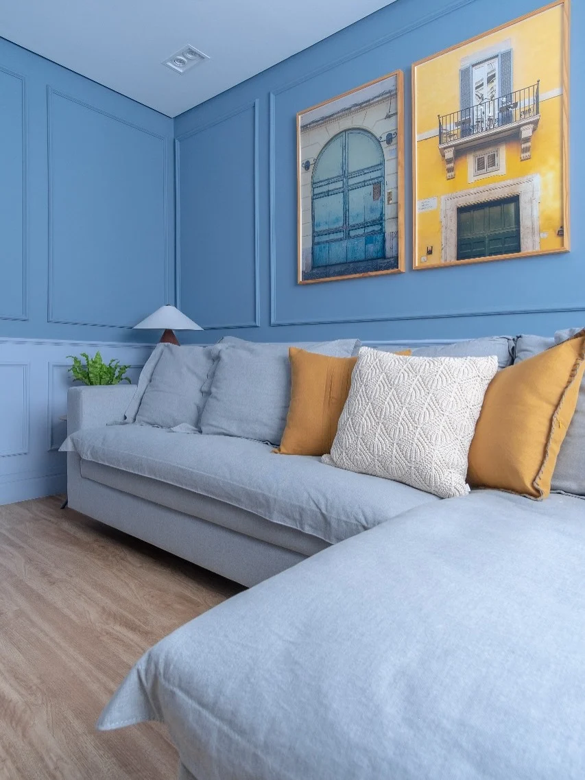 Ambiente monocromático azul com almofadas coloridas para quebrar a cor.