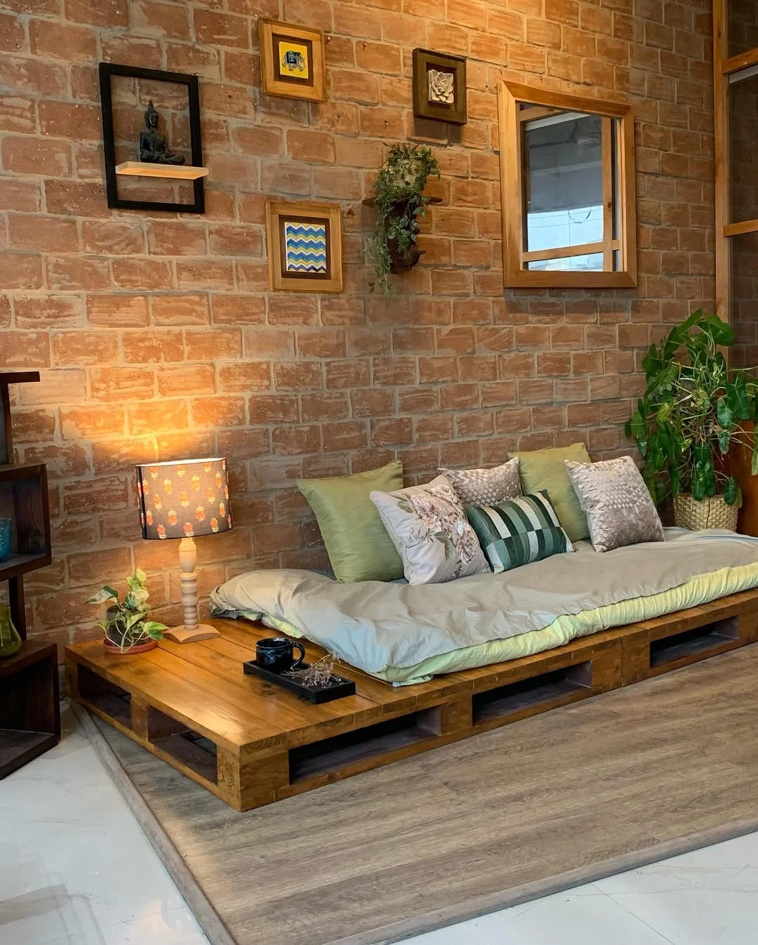 Sala de estar com móvel de pallet e parede de tijolinhos.