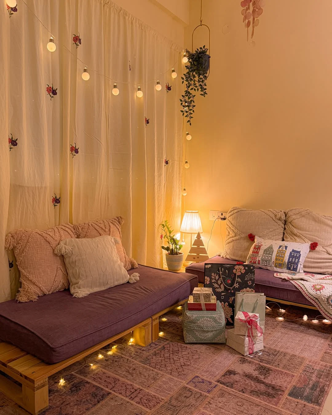 Sala jovial com luzes penduradas e sofá feito de pallet.