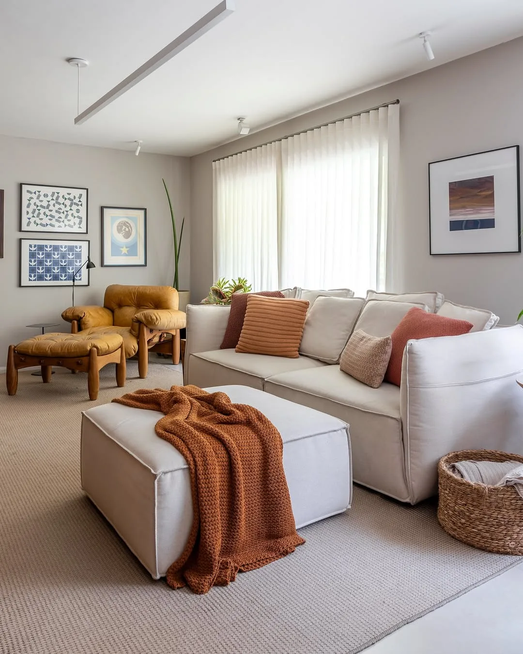 Sofá branco com contraste de almofadas em tons terrosos.