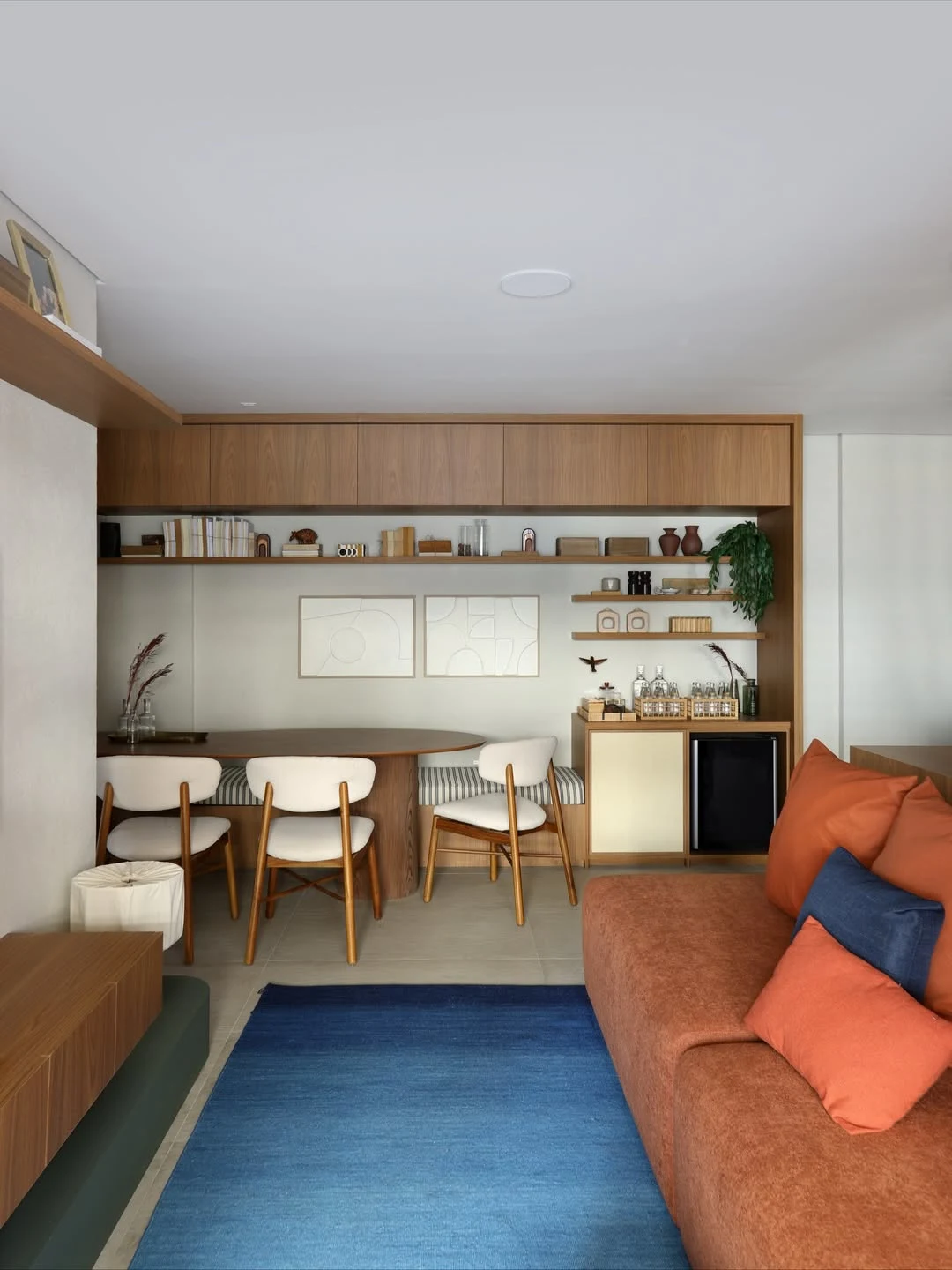 Sofá de tom terroso e almofadas em tons similares, tapete azul.