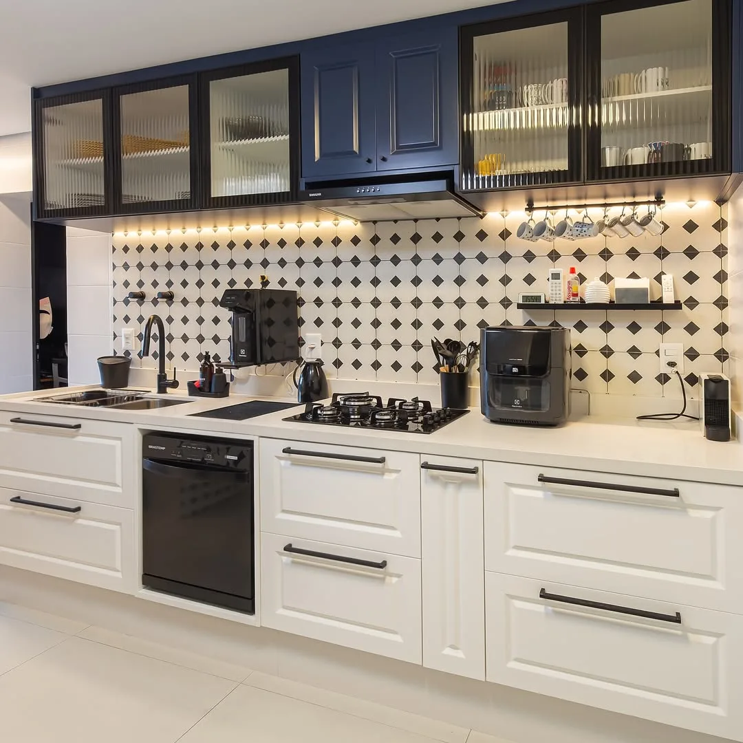Cozinha com azulejos preto e branco, armário branco e azul marinho.