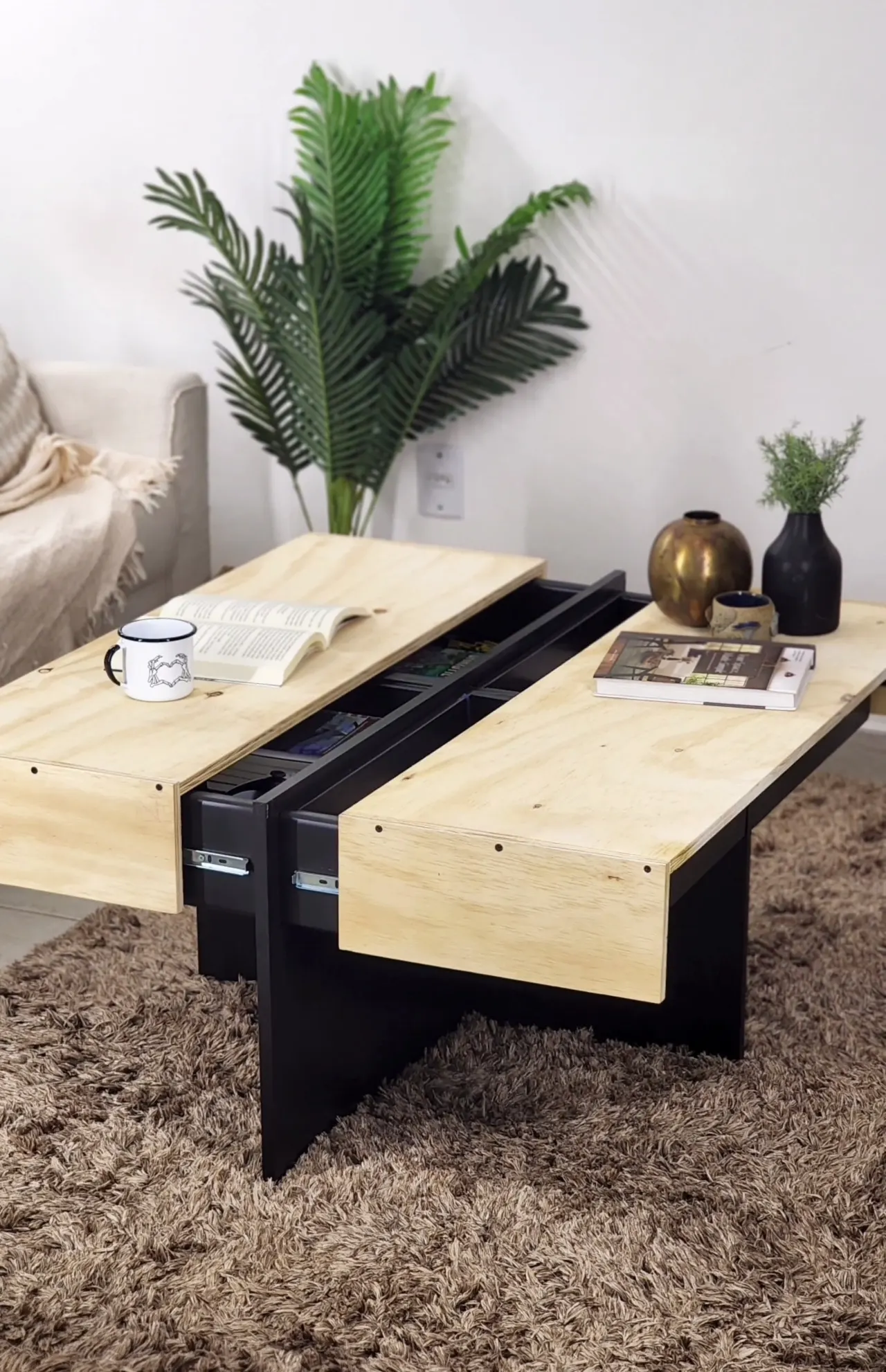 Mesa de centro com compartimento interno semi aberta, tampo de madeira e vasos em cima.