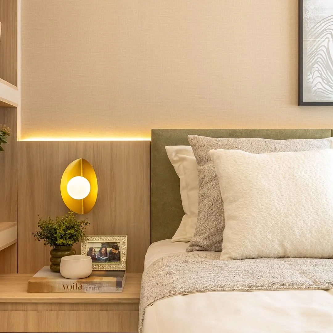 Papel de parede com linho, cabeceira verde acolchoada e luminária lateral.