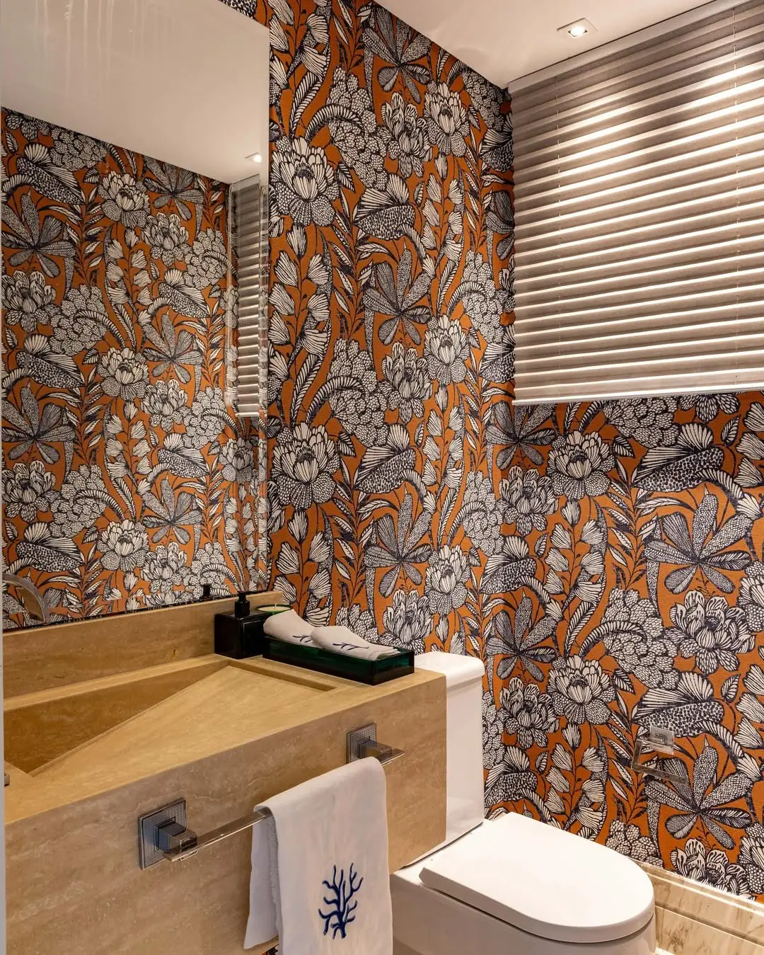 Ideia de banheiro com papel de parede maximalista e estampa forte, pia bege.