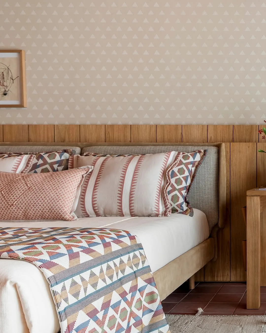 Papel de parede triangular, jogo de cama estampado, cabeceira de madeira.