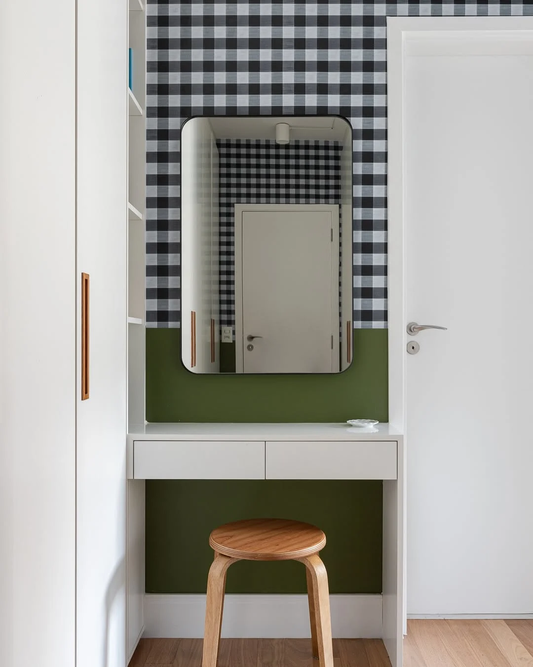 Papel de parede xadrez e meia parede verde, porta branca.