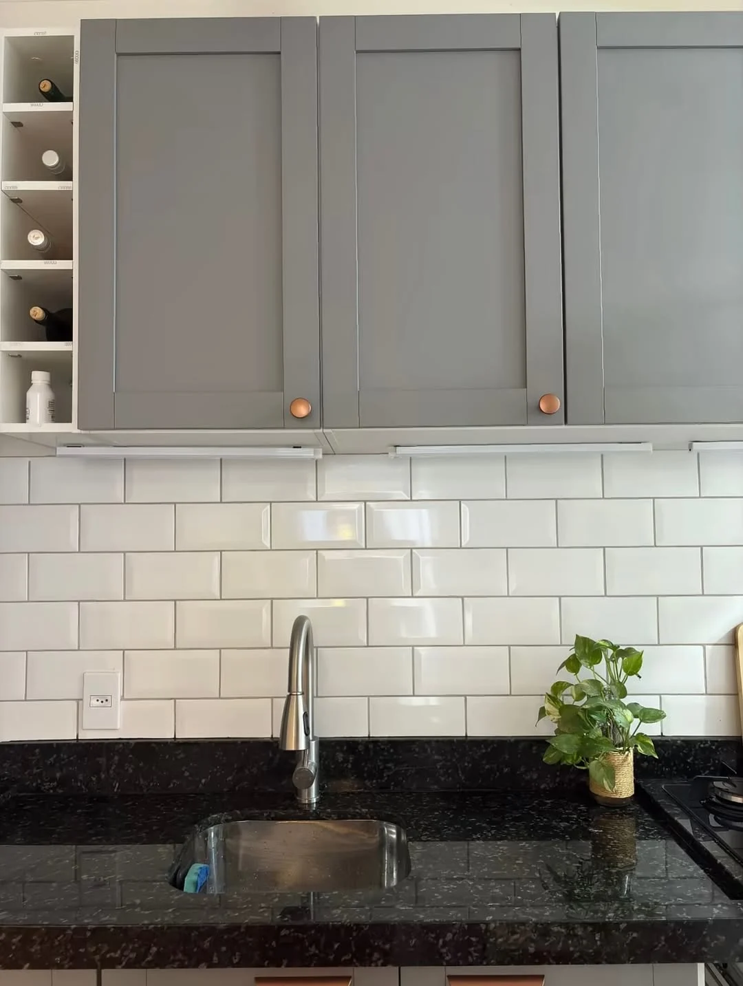 Cerâmica da cozinha de tijolinho branco e armário cinza.