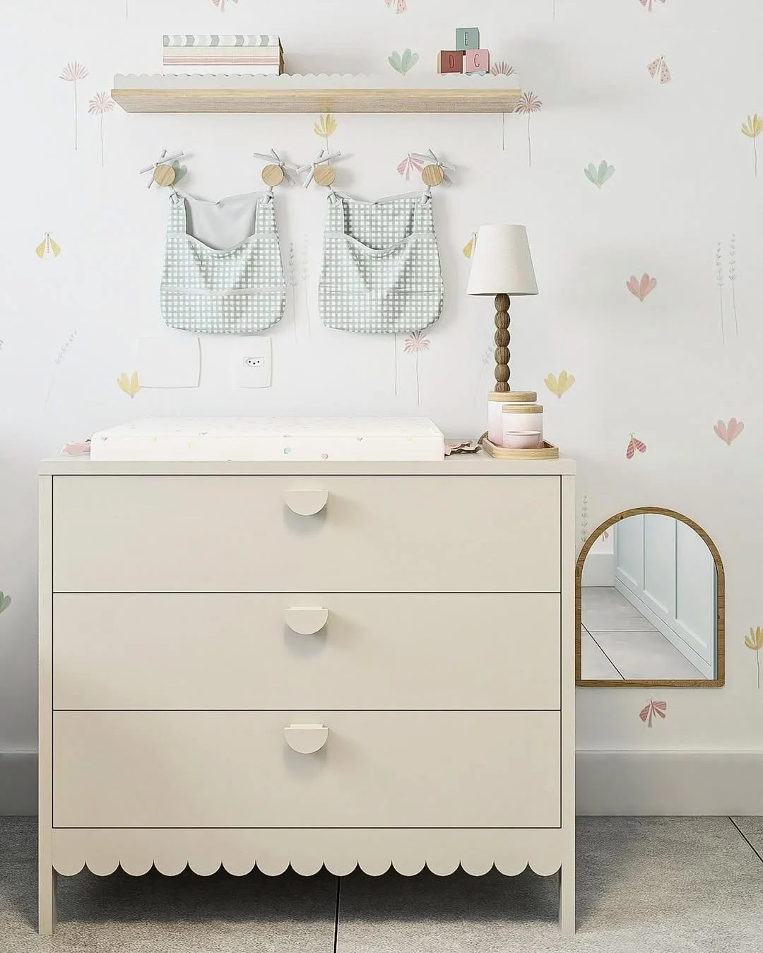 Trocador feminino com detalhes pequenos e coloridos na parede, cômoda com barrado arredondado.